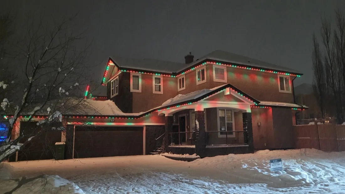 Calgary home with permanent LED lights set to Christmas red and green over fresh snow