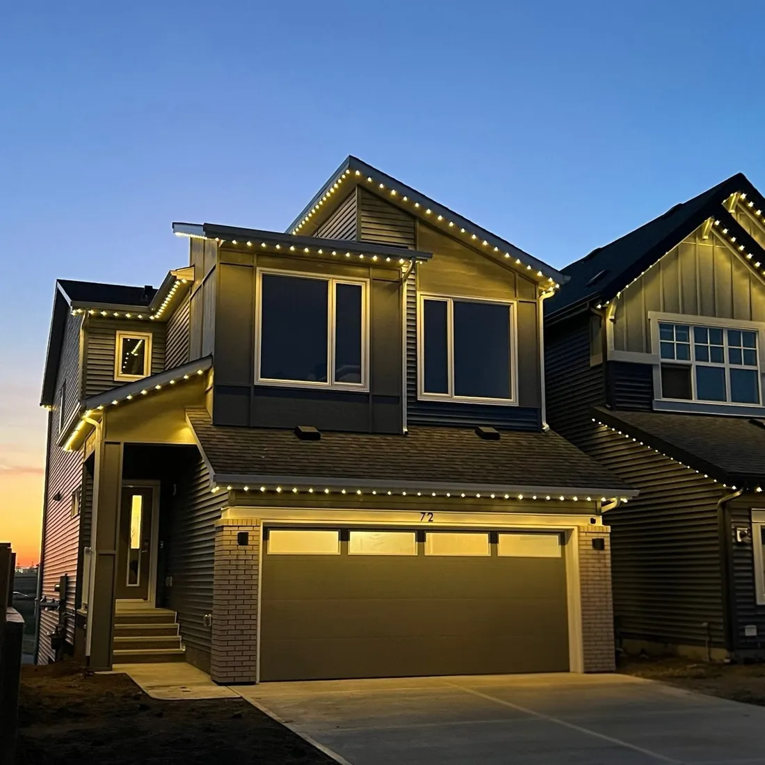 Calgary home at dusk with warm white permanent LED roofline lighting against a sunset sky