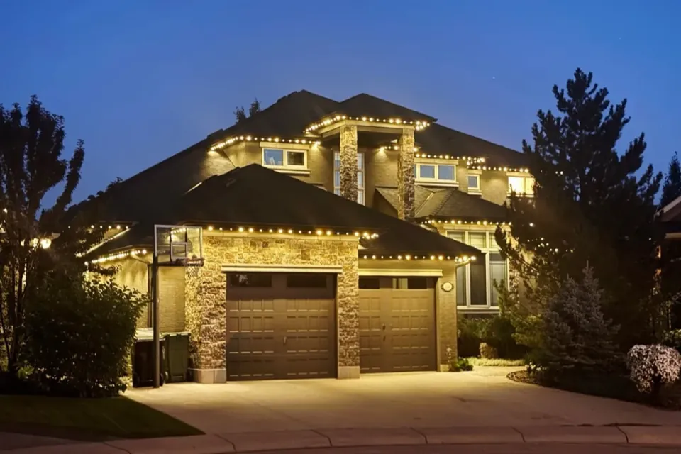Calgary two-storey home at dusk with warm white permanent LED lights along the roofline and peaks