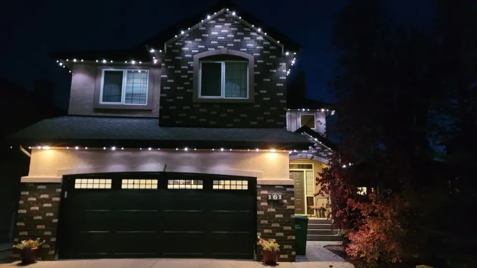 Calgary two-storey home at night with warm white permanent LED lights along the roofline and above the garage