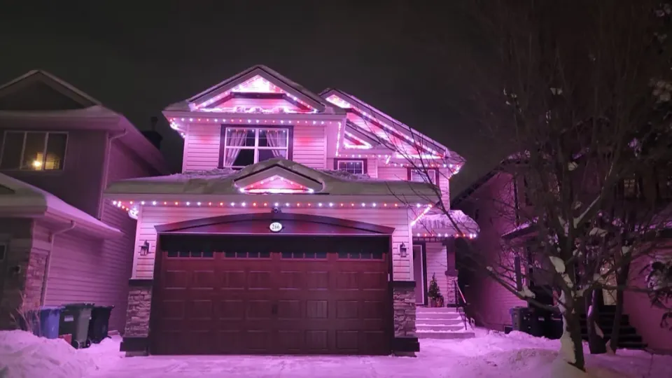 A Calgary home lit in pink permanent LED colour on a snowy winter night