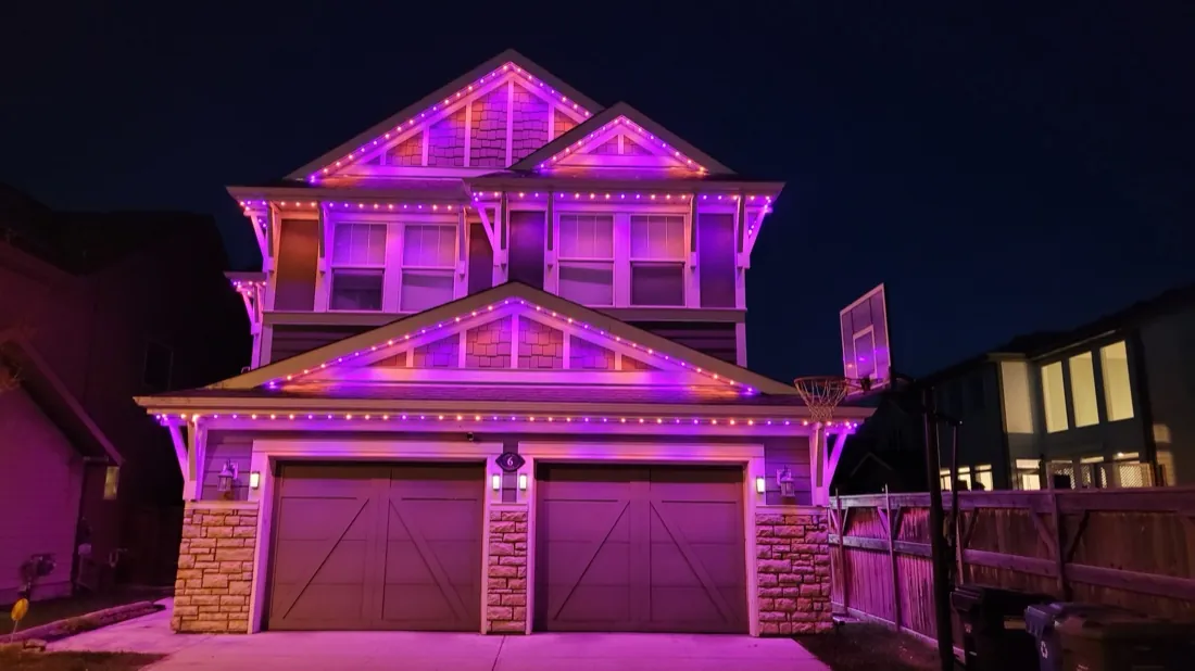 Two-storey Calgary home glowing magenta and pink with app-controlled permanent LED lighting at night