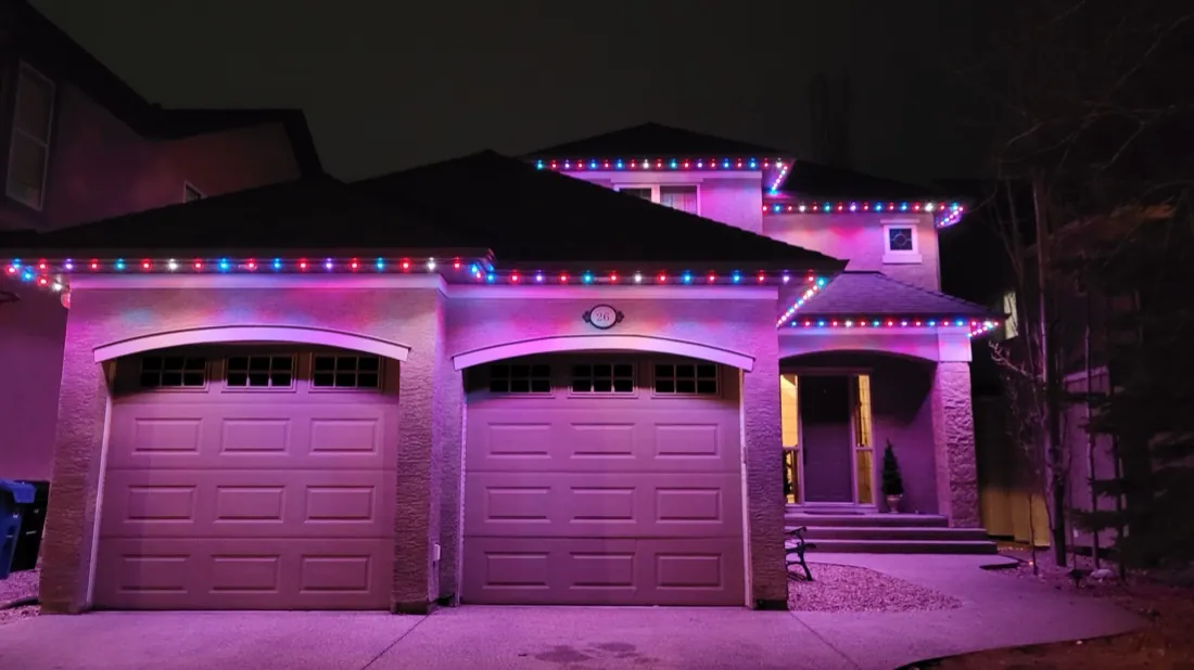 Calgary home outlined in pink and purple permanent LED lighting over double garage arches at night