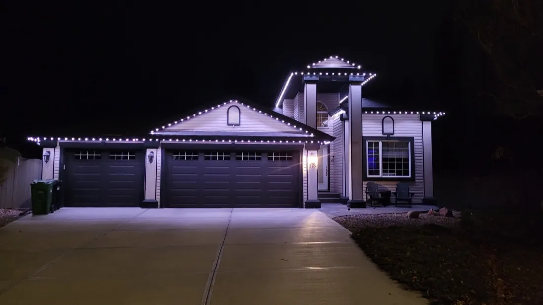 Calgary home outlined in warm white permanent LED lighting across the roofline and gables at night