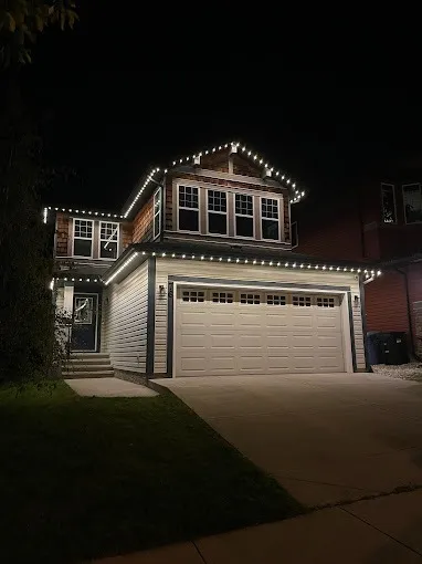 A Calgary home outlined in warm-white permanent LED lighting at night, backed by 10-year light and 5-year hardware warranties