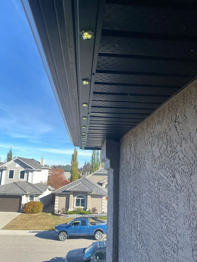 Underside of a home's soffit in daylight — individual permanent LED modules seated in the colour-matched channel
